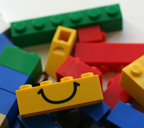 Lego-Duplo-Steine in gelb, grün blau und rot liegen durcheinander auf dem Boden.