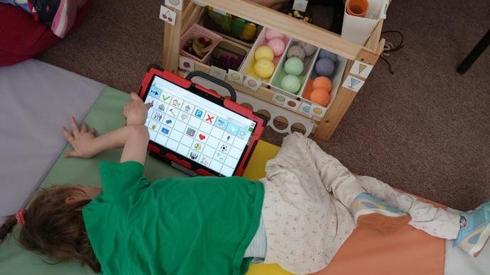 ein Mädchen liegt vor ihrem Sprachcomputer und spielt Kaufladen