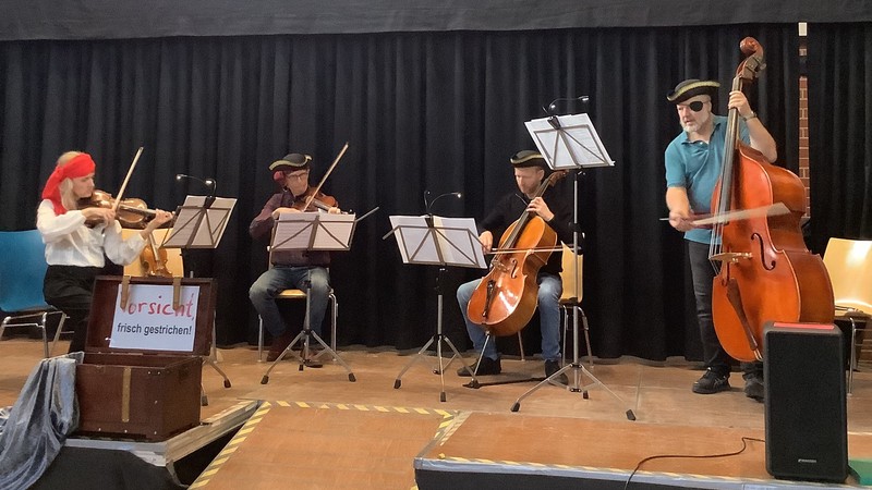 Vier Musiker mit Streichinstrumenten spielen auf der Bühne.