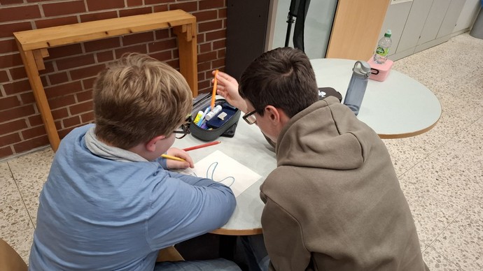 Zwei Schüler zeichnen ein Klassenschild.