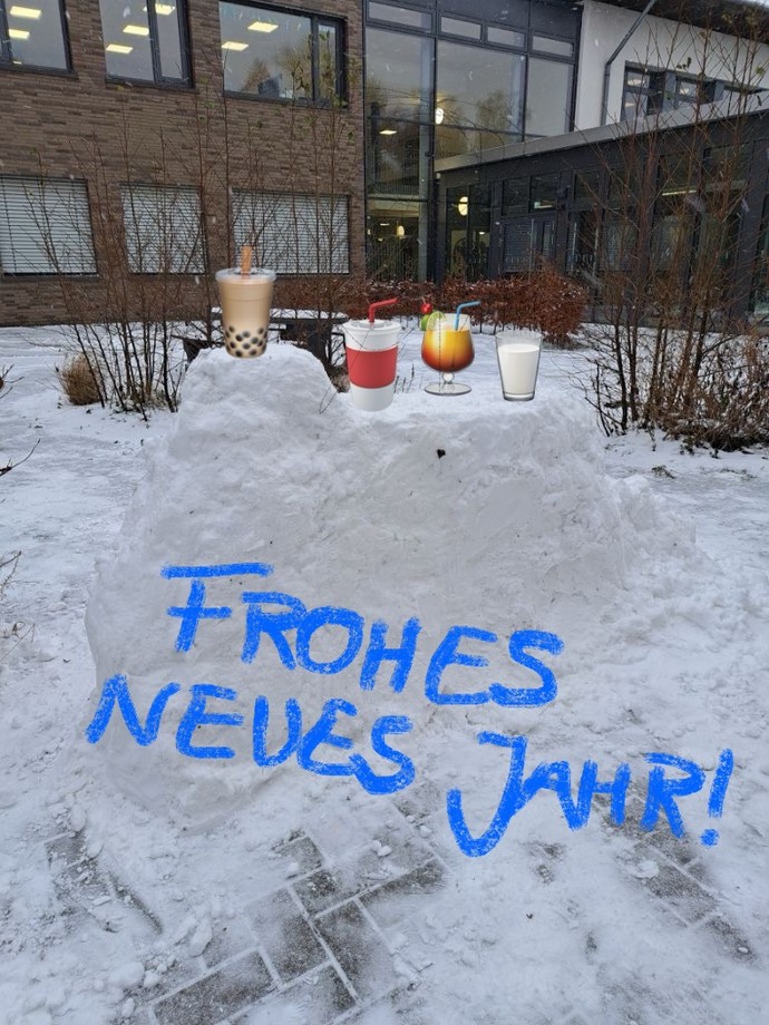 Aus Schnee ist eine Bar gebaut. Symbole mit Getränken sind hinzugefügt. Auf einem Schriftzug steht: Frohes neues Jahr.