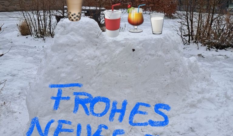 Aus Schnee ist eine Bar gebaut. Symbole mit Getränken sind hinzugefügt. Auf einem Schriftzug steht: Frohes neues Jahr.