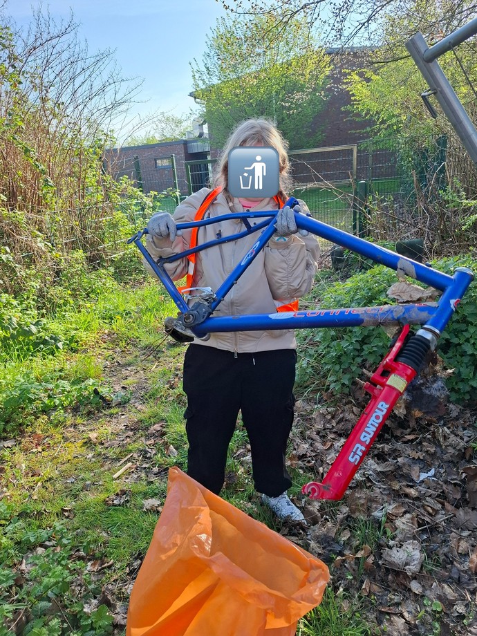 Eine Schülerin findet beim Müllsammeln ein kaputtes Fahrrad.
