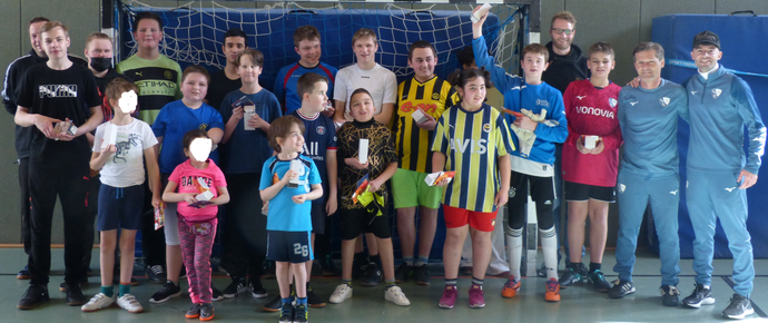 Viele Jugendliche und Erwachsene stehen mit Trainer B.Adamik und Ex-Profi D.Wosz in der Turnhalle vor einem Handballtor und lächeln in die Kamera.