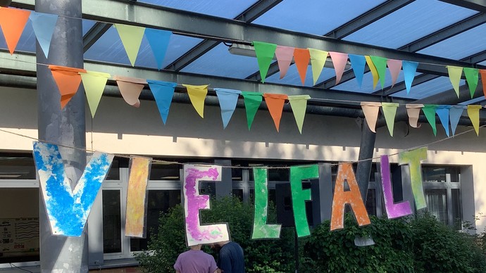 Der bunte Schriftzug Vielfalt, darüber bunte Wimpel