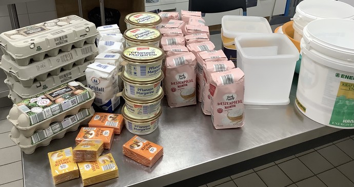 Auf einem Tisch liegen sehr viele Packungen Mehl, Zucker, Eier und Butter.