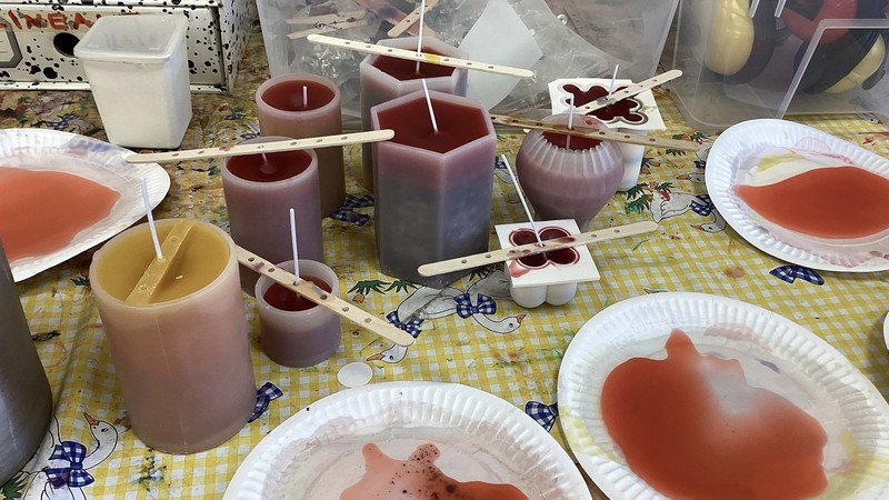 Kerzen, die gerade noch gegossen werden. Das Wachs härtet in Formen aus.