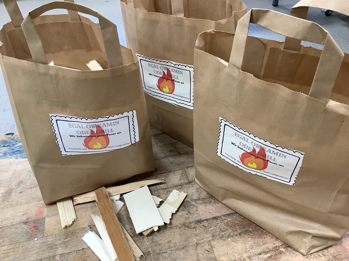 Drei Papiertüten, in denen Feuerholz abgepackt ist.
