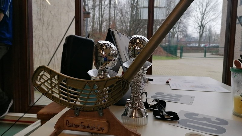 Goldener Unihoc-Schläger auf einer Holzplatte mit der Aufschrift "Rainer Fandrich Cup"