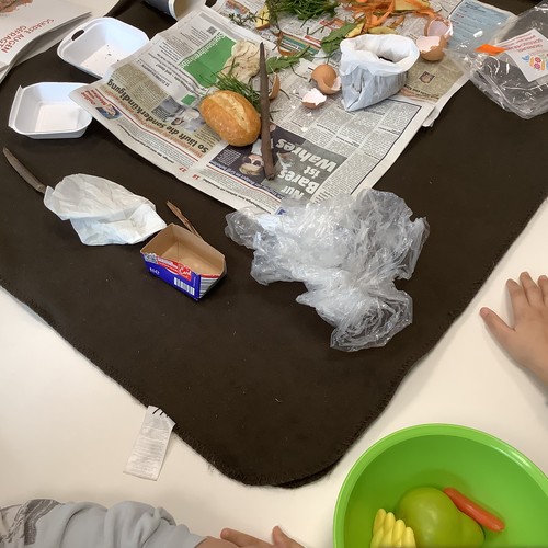 Auf einem Tisch liegen Tüten, Zeitungspapier, ein Brötchen, Eierschalen und anderer Abfall.