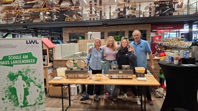 Waffelverkaufsstand im Baumarkt mit vier lachenden Personen.