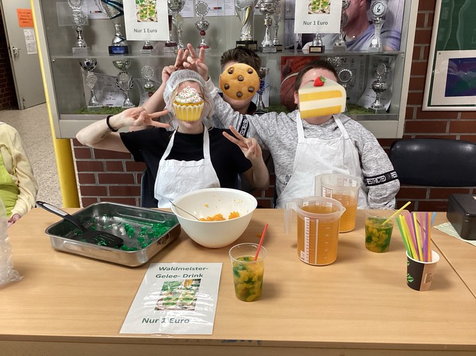 SchülerInnen sitzen hinter Tischen und verkaufen Snacks.