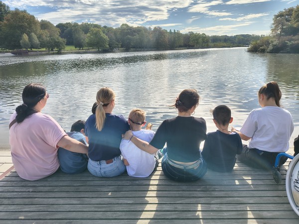 Kinder und Erwachsene sitzen auf einem Steg und schauen aufs Wasser