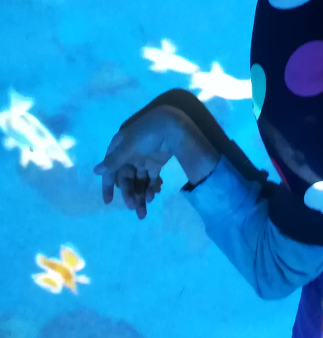 Buntes Lichtspiel auf einer Matte auf der die Hand eines Jugendlichen liegt.