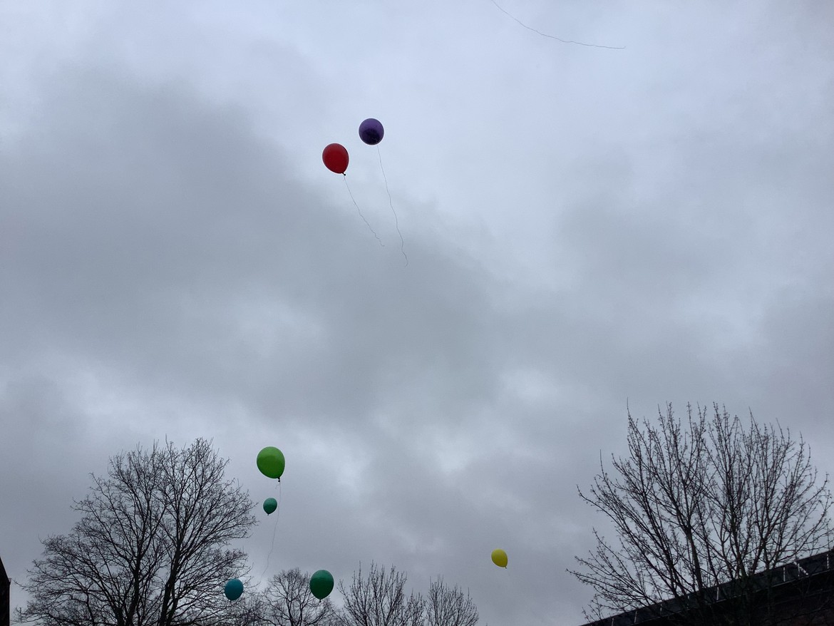 mehrere bunte Luftballons steigen in einen wolkenverhangenen Himmel auf