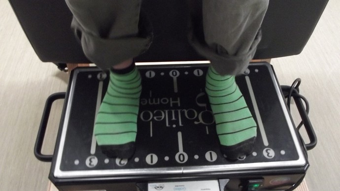 Eine Person steht auf der Vibrationstrainingsplatte "Gallileo". Nur die Füße sind zu sehen.