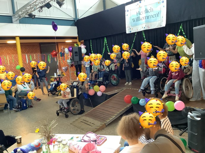 Viele Kinder und Erwachsene mit Masken auf einer Bühne.