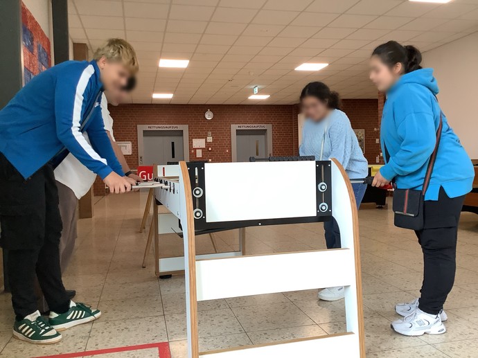 Vier SchülerInnen spielen stehend am neuen Kicker.