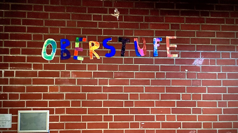 Der Text "Oberstufe" ist mit bunten Holzbuchstaben an der Wand befestigt