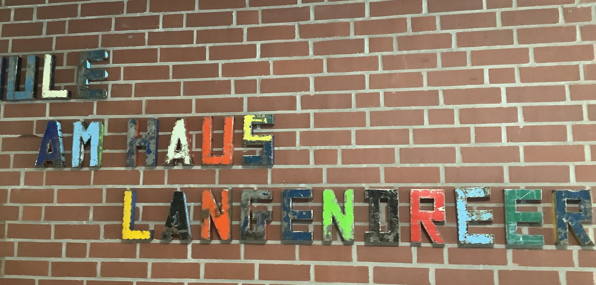 Bunte Metallbuchstaben an einer Ziegelwand "Schule am Haus Langendreer"