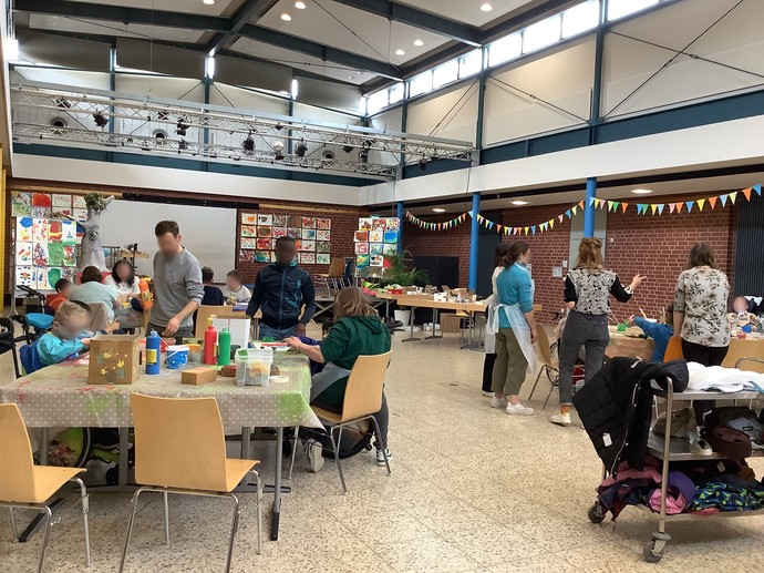 Schülerinnen und Schüler sitzen an Tischen im Forum. Es wird gemalt, gestempelt und geklebt.