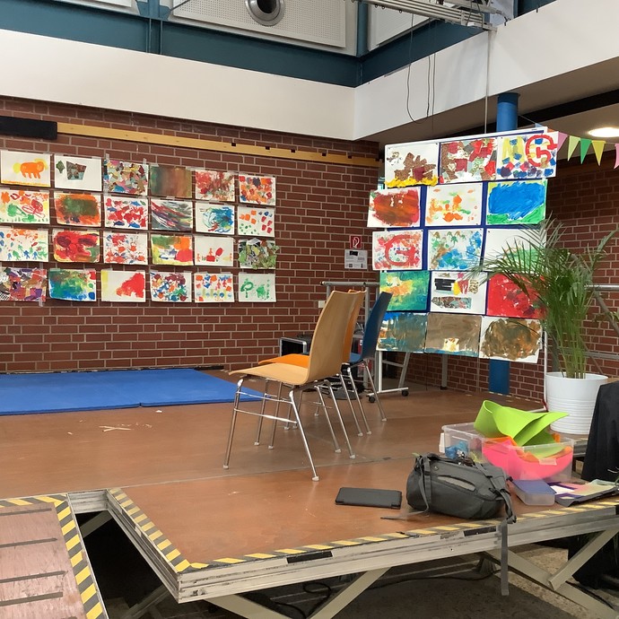 Ausgestellte Kunstwerke an der Wand und an einer Stellwand.