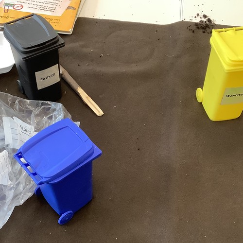 Drei Modell-Mülltonnen in blau, schwarz und gelb