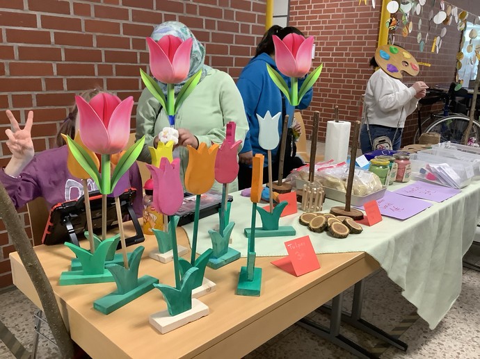 SchülerInnen sitzen hinter Tischen und verkaufen Holzblumen.