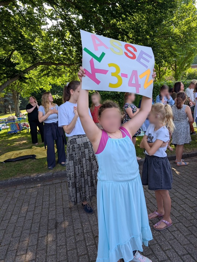 Ein Mädchen hält ein buntes Schild hoch.