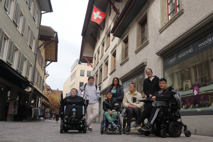 Gruppenbild in einer Fußgängerzone. Im Hintergrund weht die Schweizer Flagge.