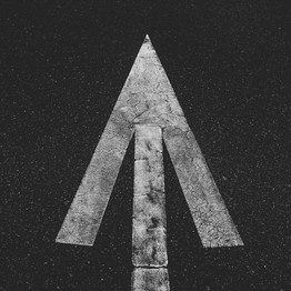 Ein weißer Pfeil auf dunkelm Asphalt