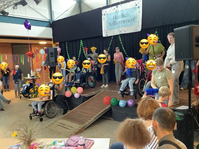 Viele kinder und Erwachsene mit Masken auf einer Bühne.