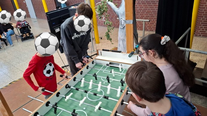 Spielszene aus einem Kickerspiel. Vier Personen spielen.