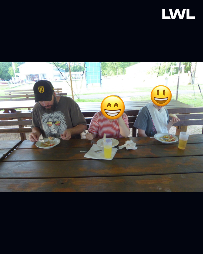 Drei Personen sitzen draußen am Tisch und essen.