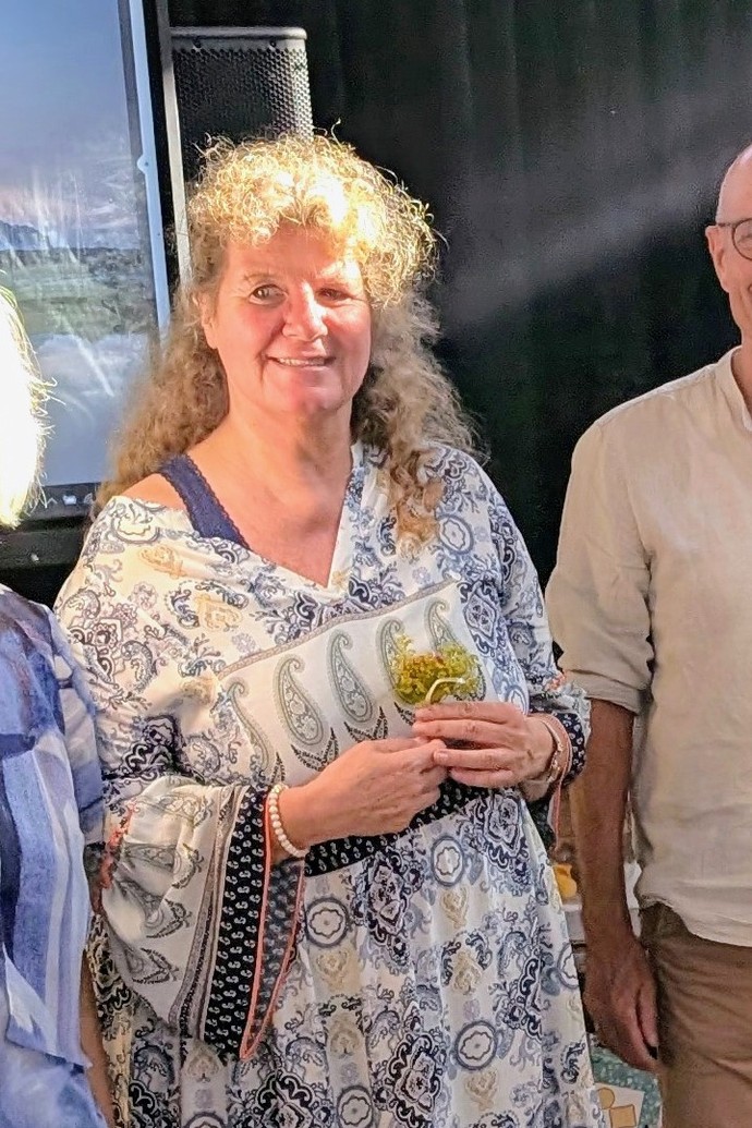 Frau Immich wendet den Blick zur Kamera und lacht.