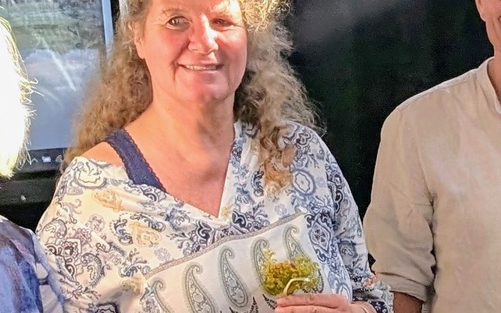 Frau Immich wendet den Blick zur Kamera und lacht.