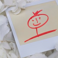 Ein rot gezeichnetes Strichmännchen auf einem Polaroid-Foto liegt auf weißen Papierschnipseln.
