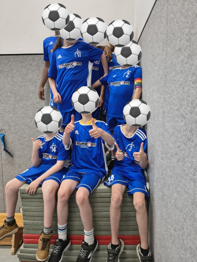 Ein Gruppenbild der Fußballmannschaft sitzend auf einem Mattenstapel