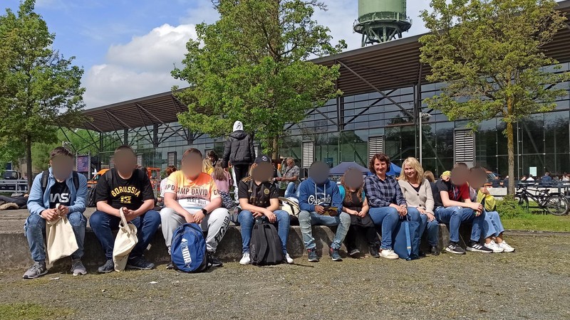 8 Jugendliche sitzen mit zwei Erwachsenen vor der Bochumer Jahrhunderthalle